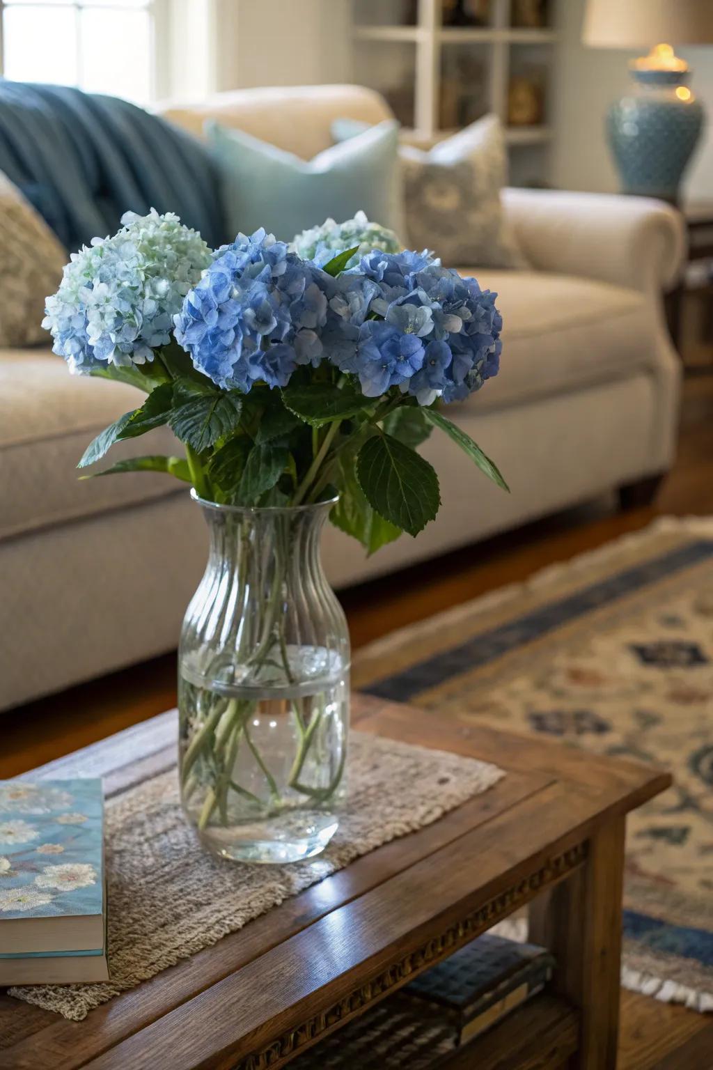 A glass vase with blue hydrangeas adds a pop of color to a cozy living room.